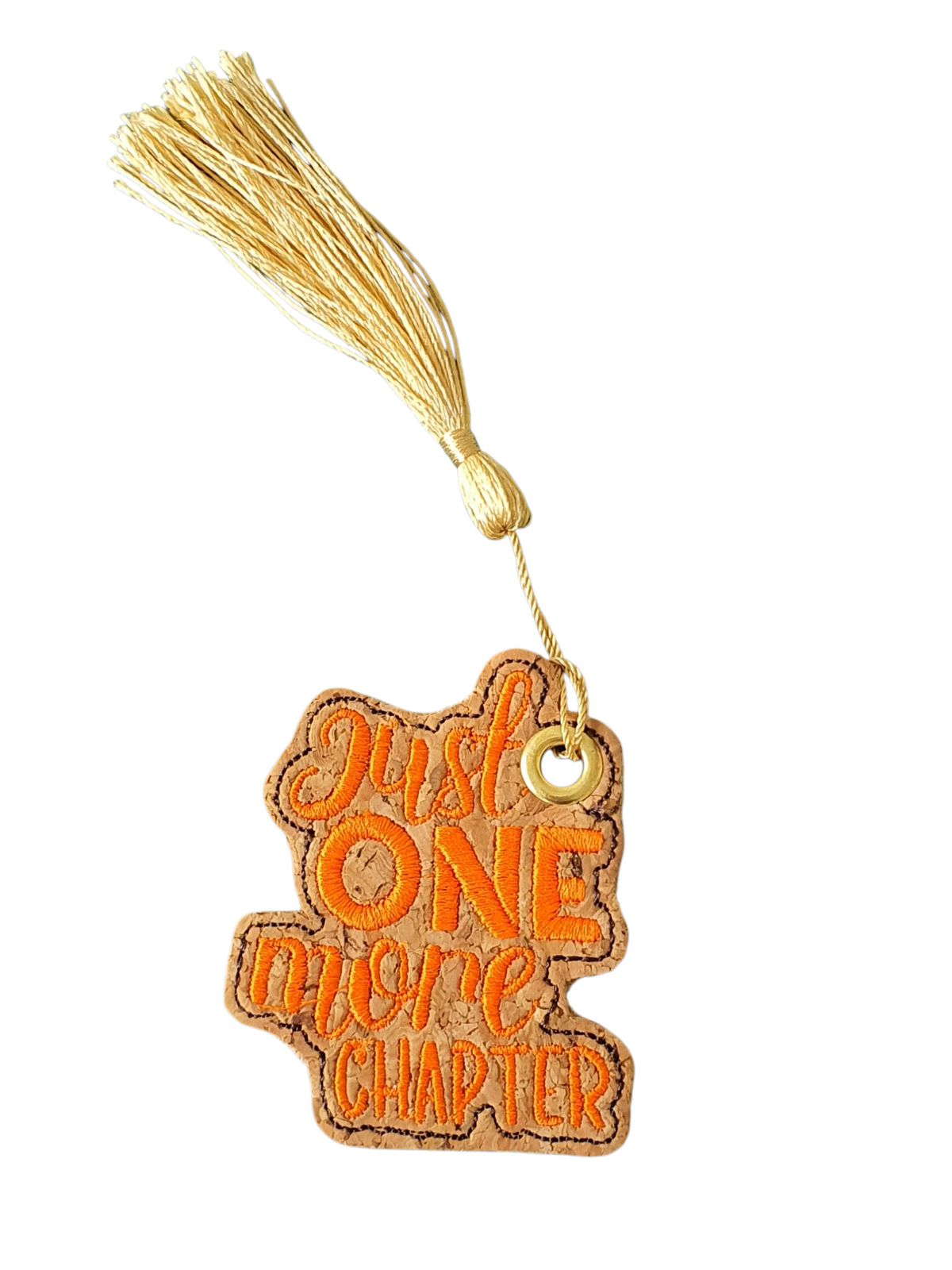 Orange embroidered 'Just One More Chapter' on cork fabric with an eyelet and gold coloured tassel.