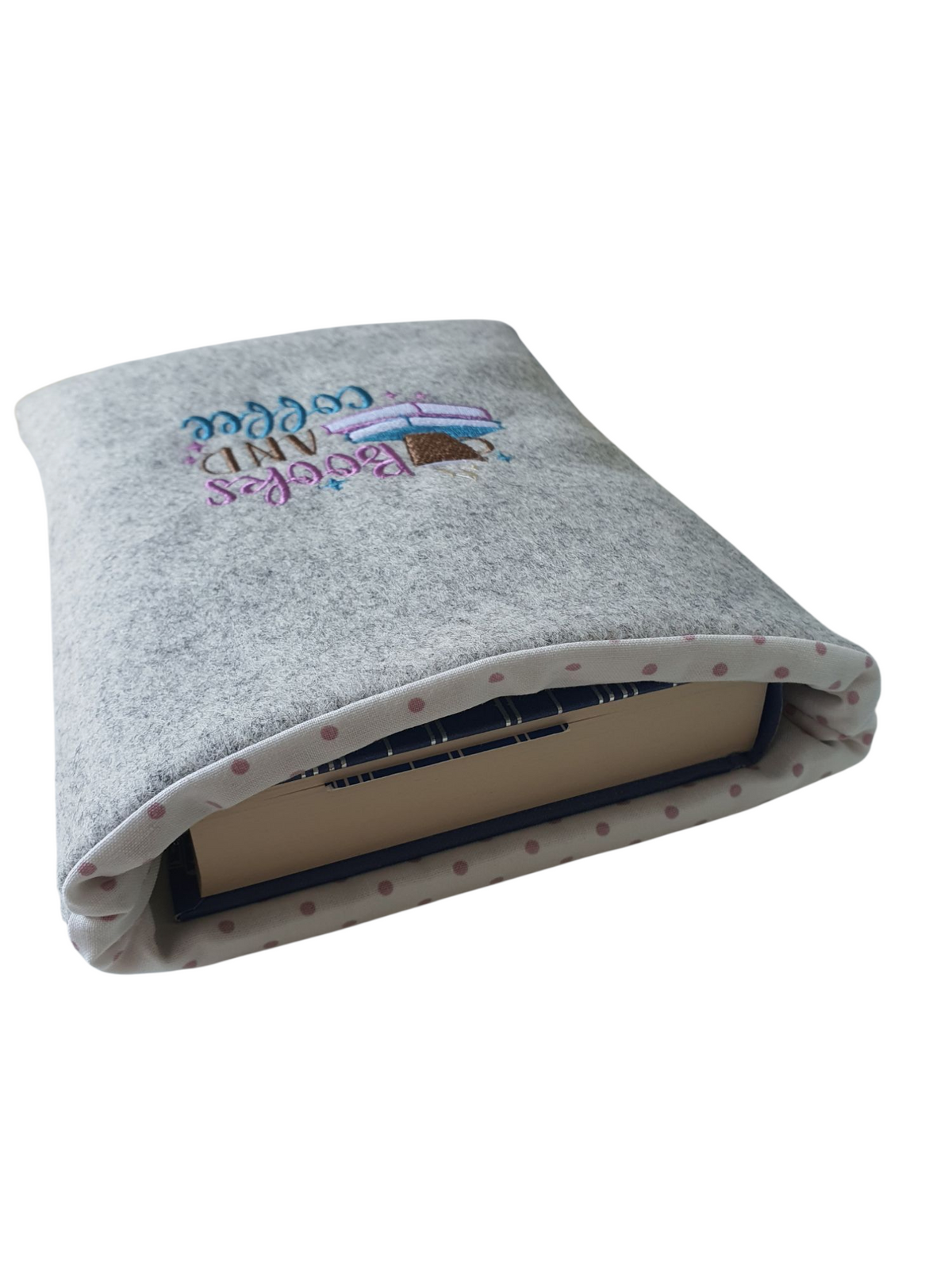A photo showing the book protecting a medium hardback book.  The photo also shows the complementing polka dot fabric which lines the handmade Book Pouch.