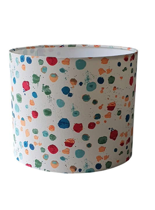 Splat Paintbox drum lampshade with multicoloured paint-like dots on pale fabric.