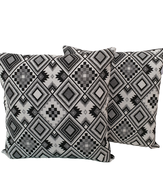 Two monochrome geometric tapestry cushion covers showing the patterned fronts